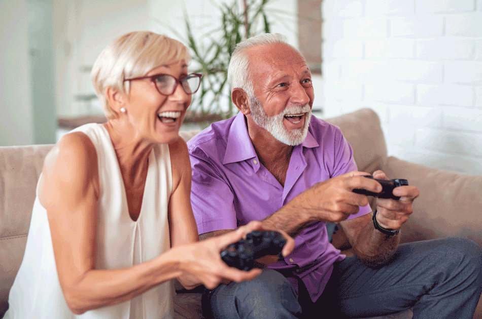 Zwei Senioren spielen auf der Couch Videospiele