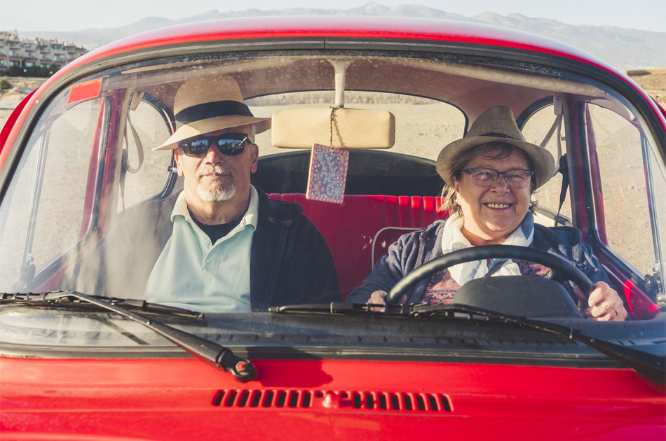 Ein Seniorenpaar sind mit dem Auto unterwegs.