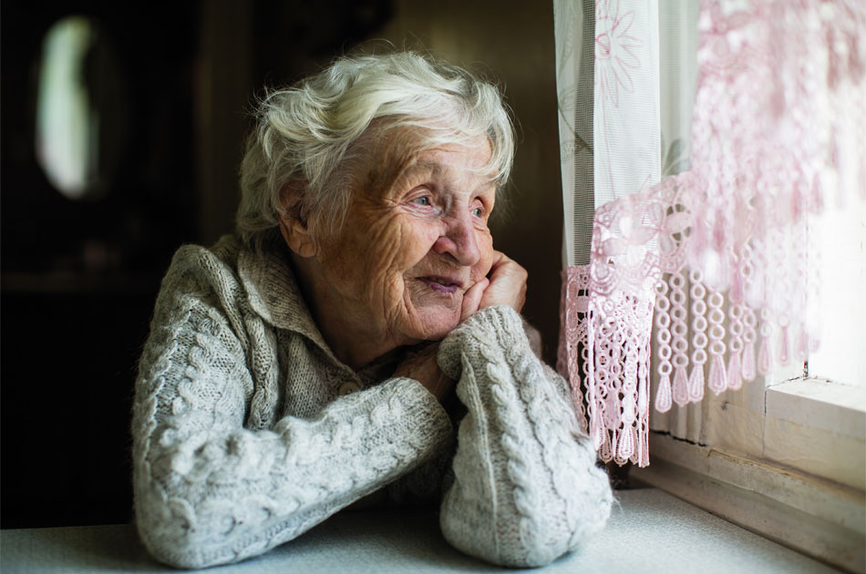 Eine ältere Frau schaut aus dem Fenster.