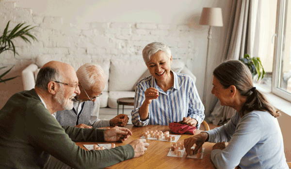 Vier Senioren spielen Bingo an einem Tisch. 