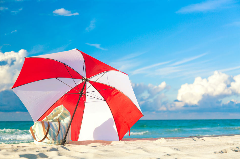 Sonnenschirm und Strandtasche am Meer.