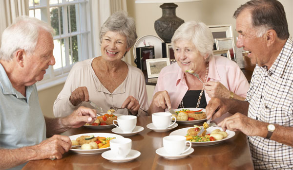 Vier Senioren unterhalten sich beim Mittagessen.