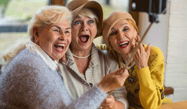 Drei Seniorinnen machen ein Selfie von sich und lachen dabei in die Kamera.